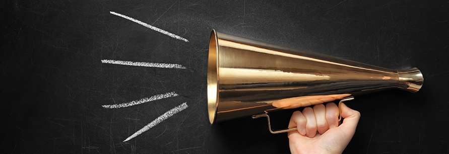 Person holding retro megaphone near black chalkboard