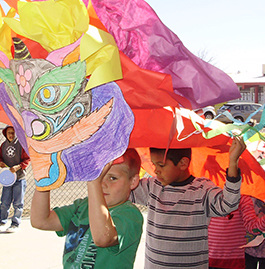 Student holding paper dragon above his head with students behind him