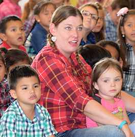 Woman in checkered shirt sits with children